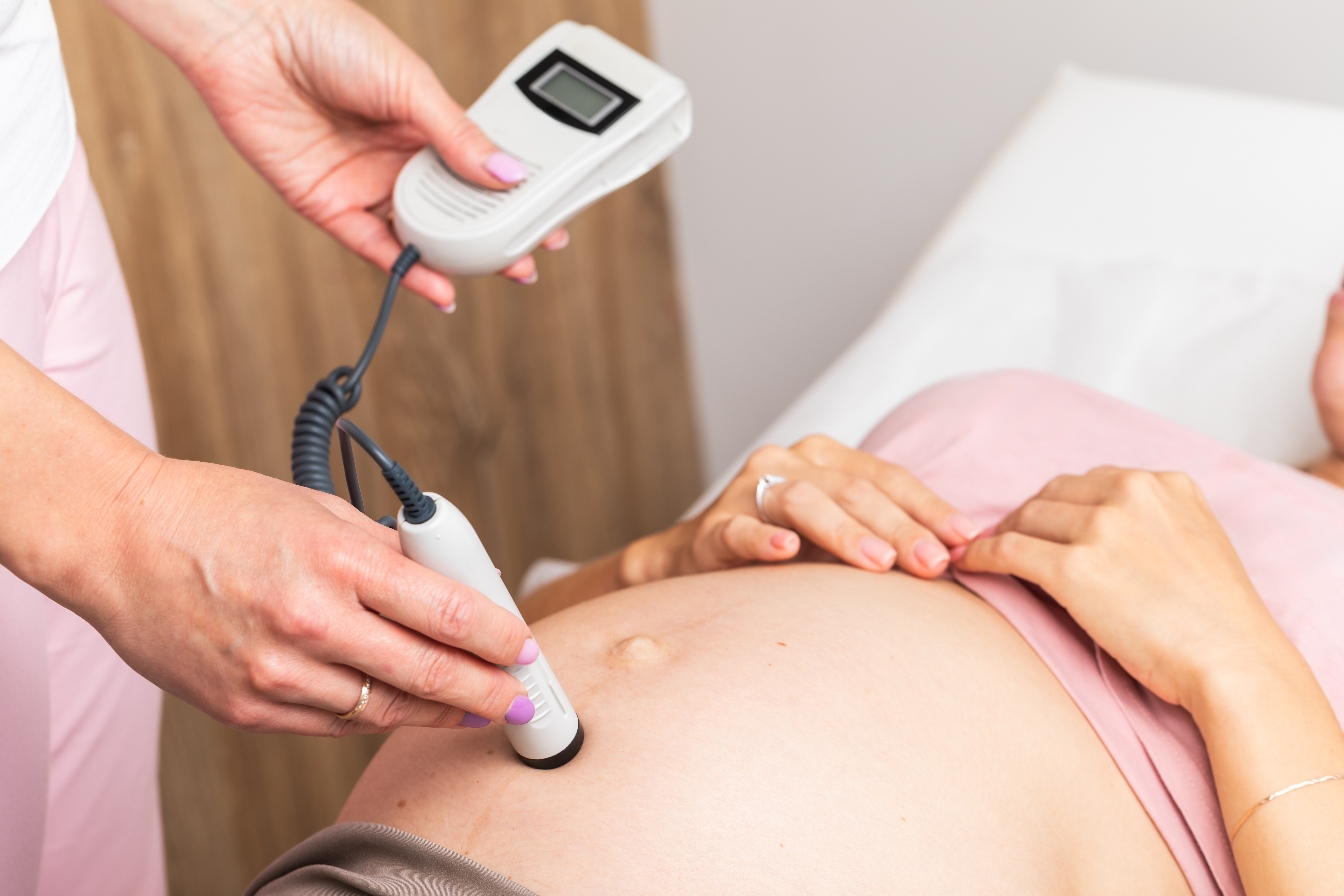 Sage-femme mesurant les battements du cœur du bébé sur le ventre d’une future maman, lors d’un suivi de grossesse à domicile Sage-femme mesurant les battements du cœur du bébé sur le ventre d’une future maman, lors d’un suivi de grossesse à domicile